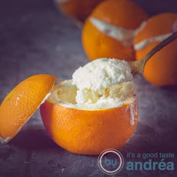 A square photo of an orange filled with orange bavarois from which a spoonful of bavarois is scooped.