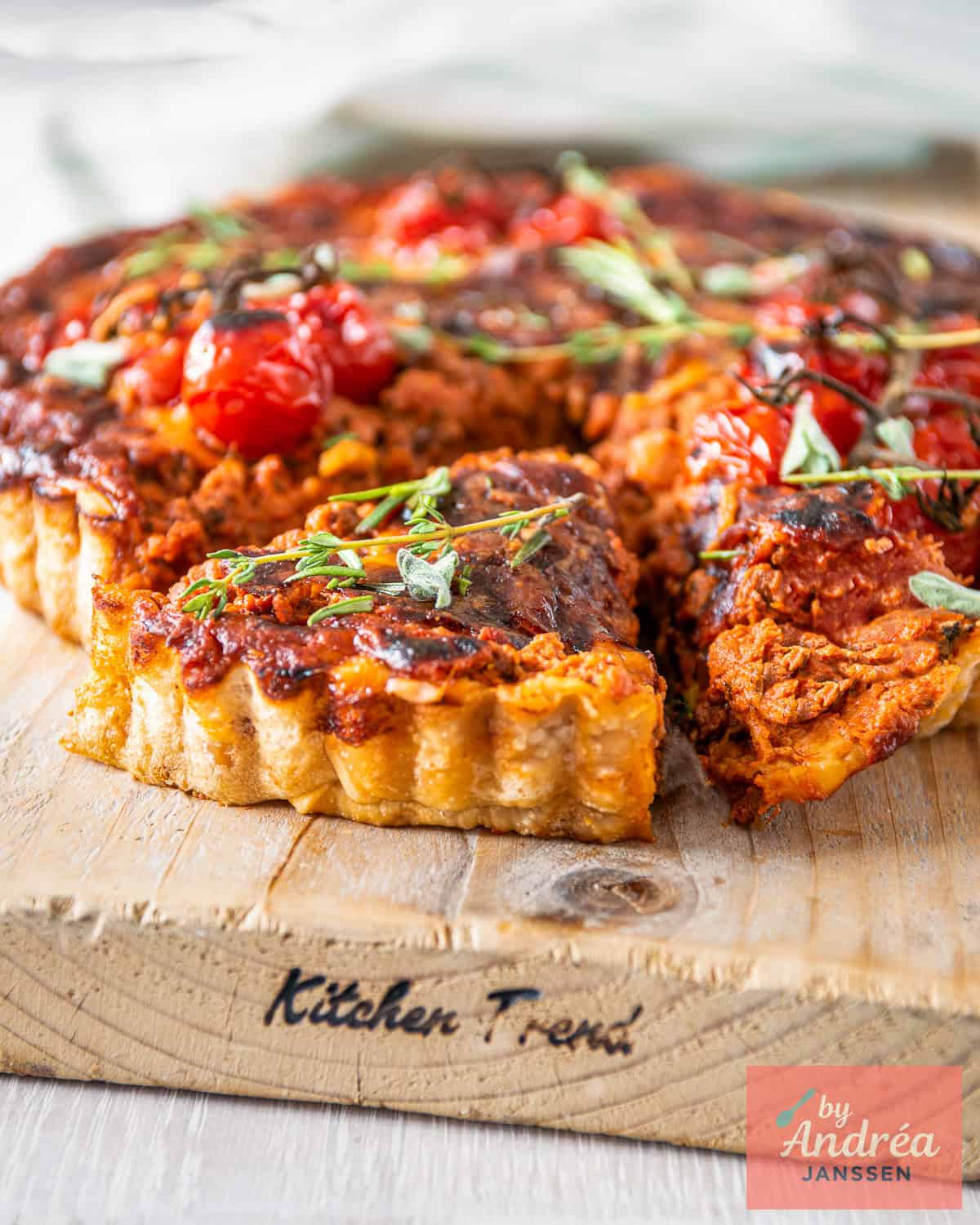 A bolognese quiche on a wooden board with a wedge cut out.