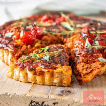 A square photo of a bolognese quiche with a slice cut out of it.