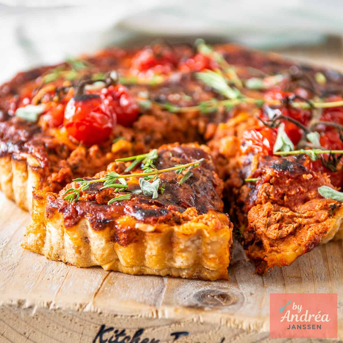A square photo of a bolognese quiche with a slice cut out of it.