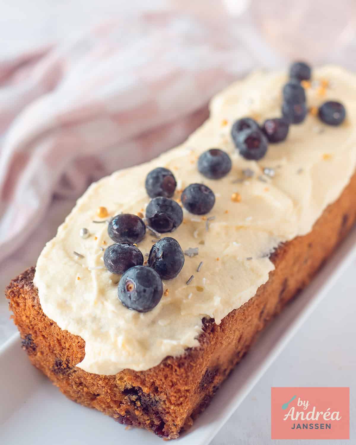 A photo of a cake with blueberry frosting and blueberries as garnish,