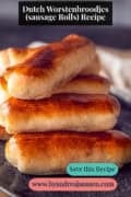 Part of a grey plate with a stack of Brabantse worstenbroodjes. A text on top: Dutch worstenbroodjes (sausage rolls) recipe