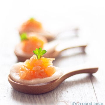 three bamboo spoons topped with a prawn cracker with smoked salmon