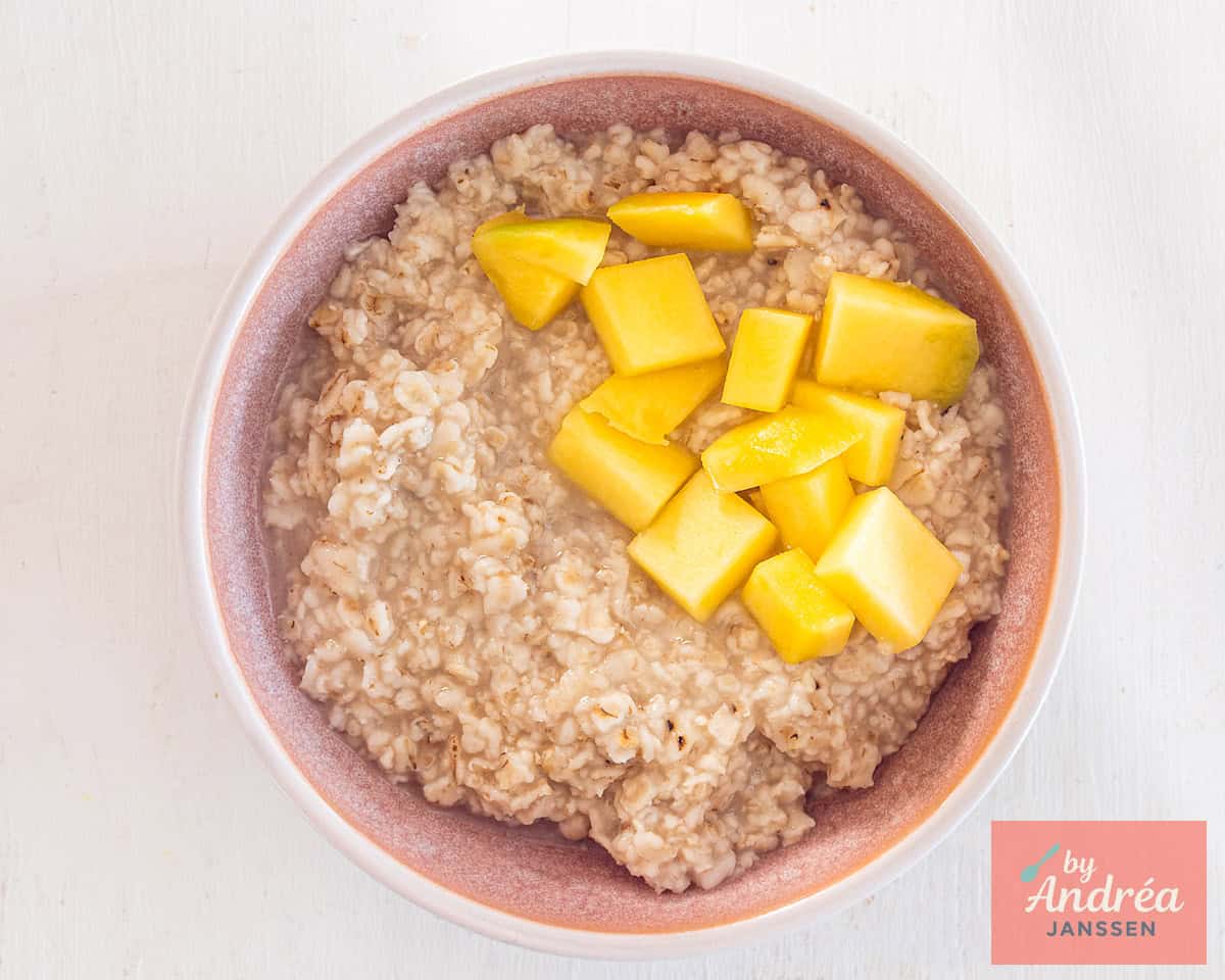 A pink bowl of oatmeal and mango