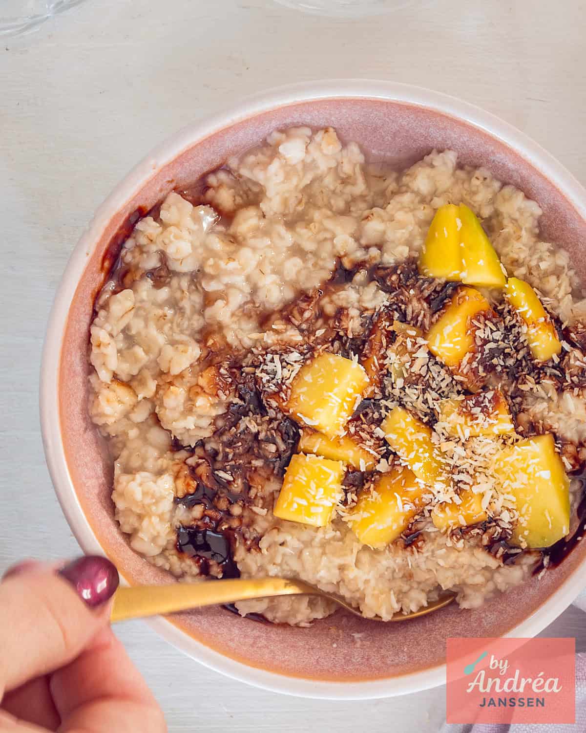 A photo from above of a bowl of oatmeal, mango, date syrup, and coconut.