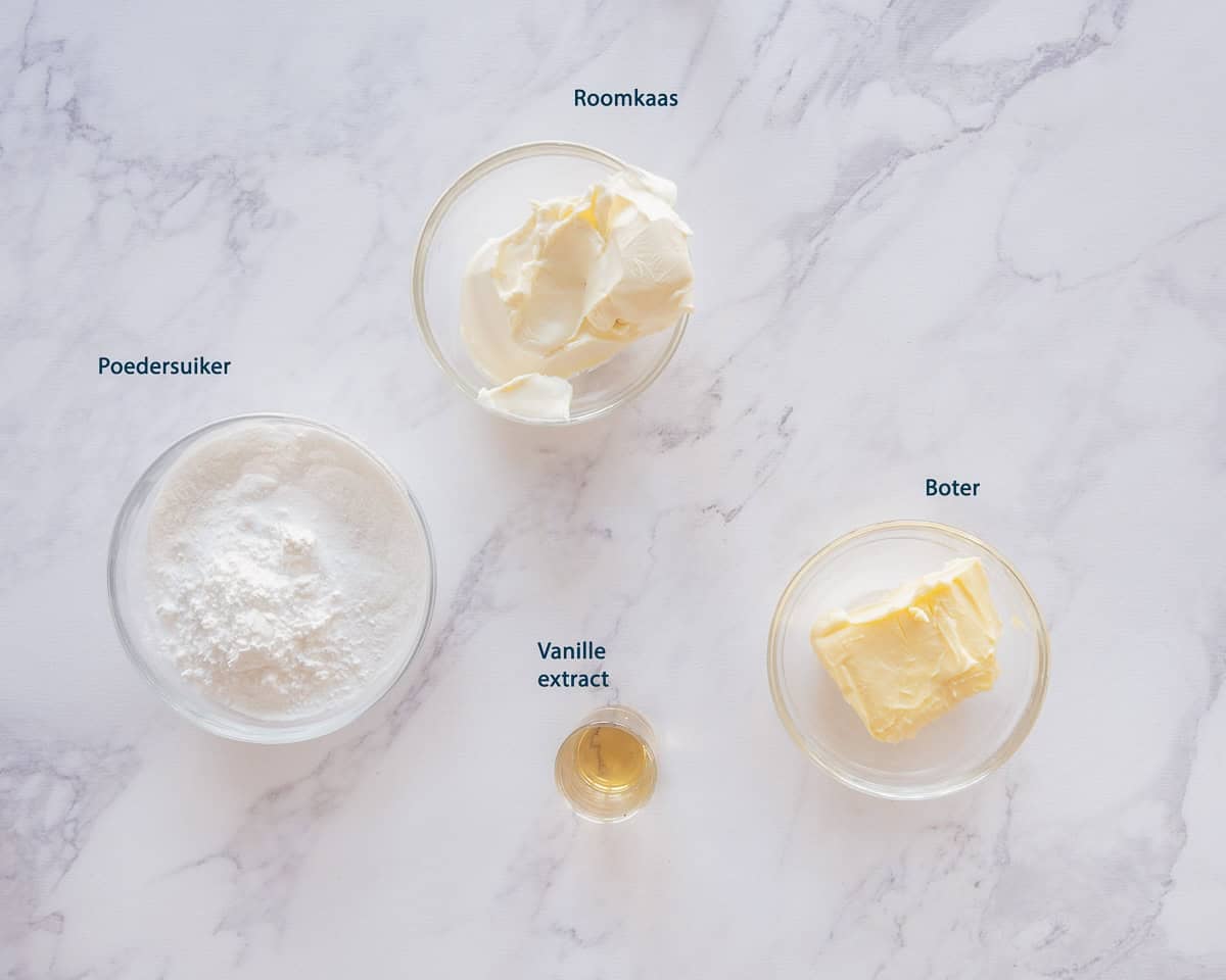 Ingredienten roomkaas frosting op een wit marmeren ondergrond met tekstbeschrijving.