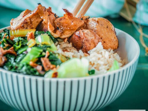 A square photo with a white striped bowl containing bok choy, rice and sticky ketjap chicken.