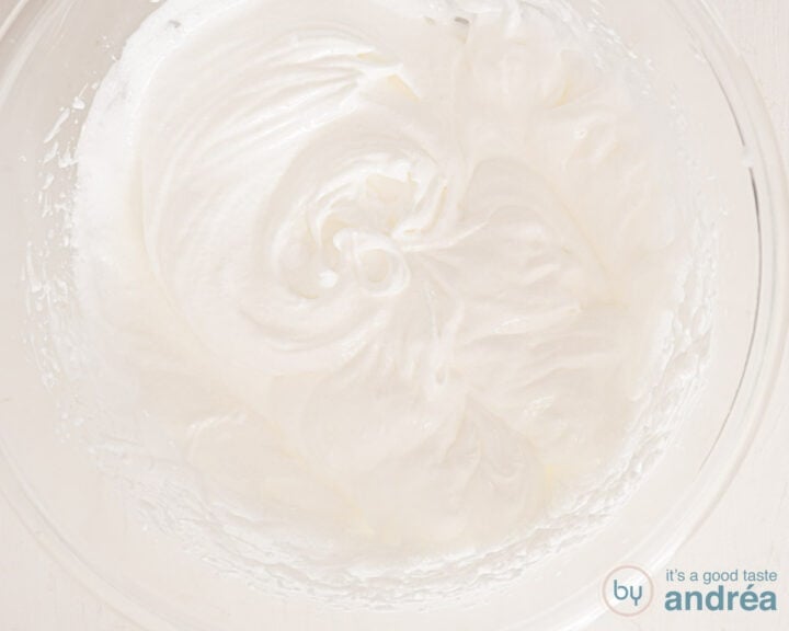 Egg white foam whipped in a glass bowl on a white surface