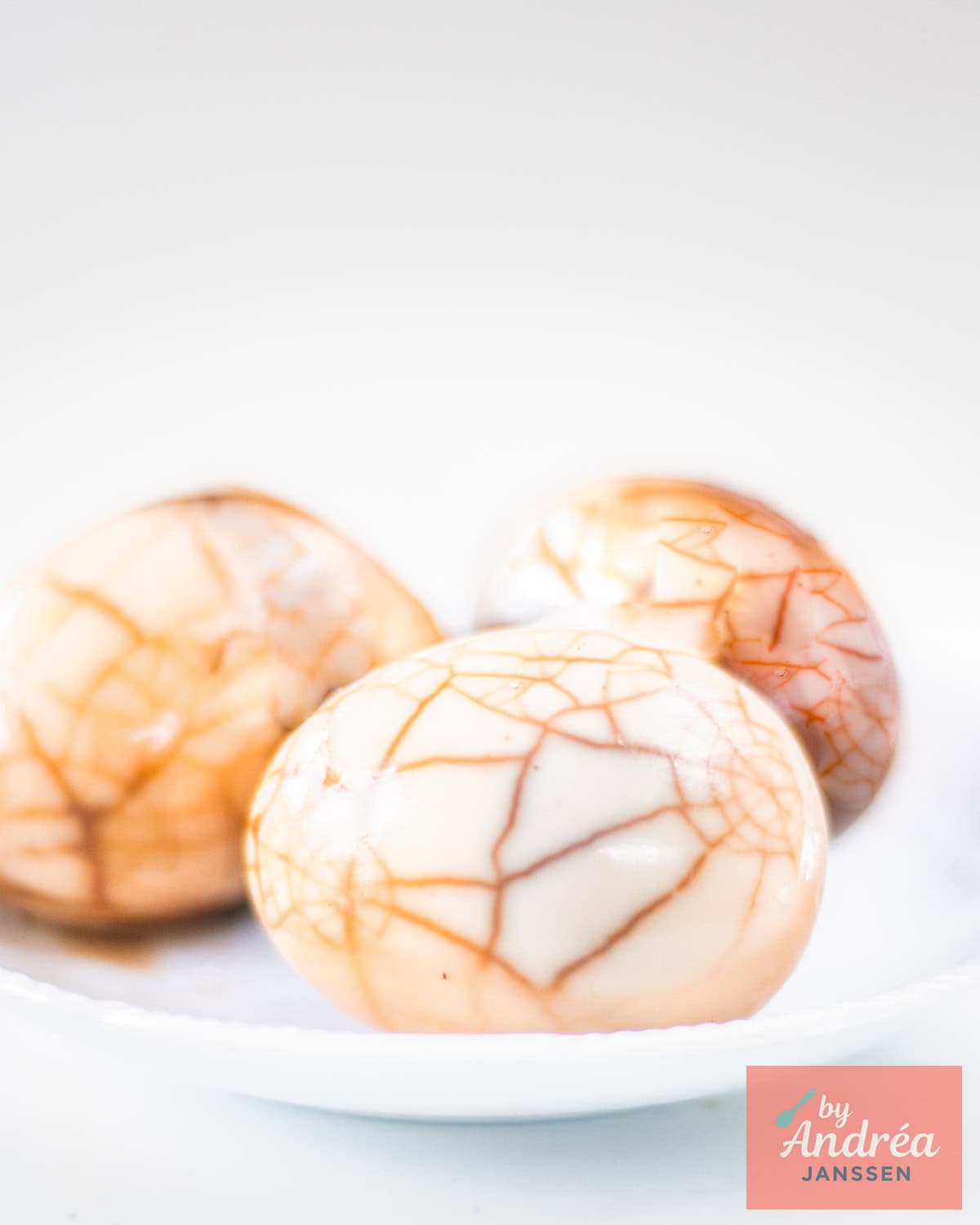 Three marbled Chinese tea eggs on a white plate.
