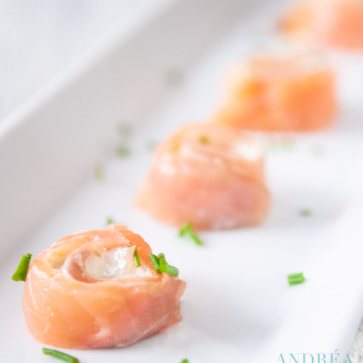 a white plate with 4 smoked salmon spirals with cream cheese