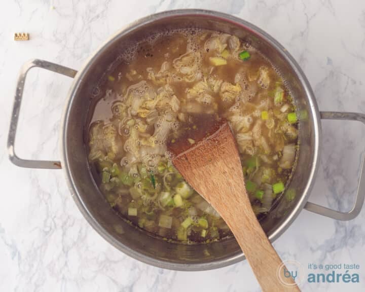 A pan filled with leek, stewed cabbage, butter and stock.