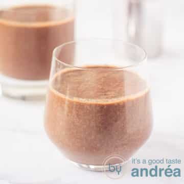 A square photo with two glasses filled with a smoothie with coconut water, cocoa, cherries and spinach. On a white background