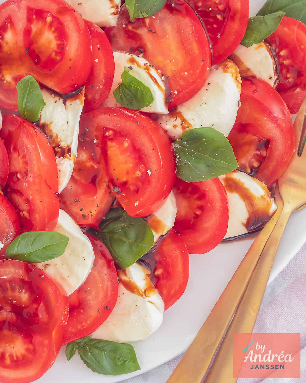A top-down photo of tomato slices, mozzarella, basil and balsamic vinegar on a white platter: the caprese salad