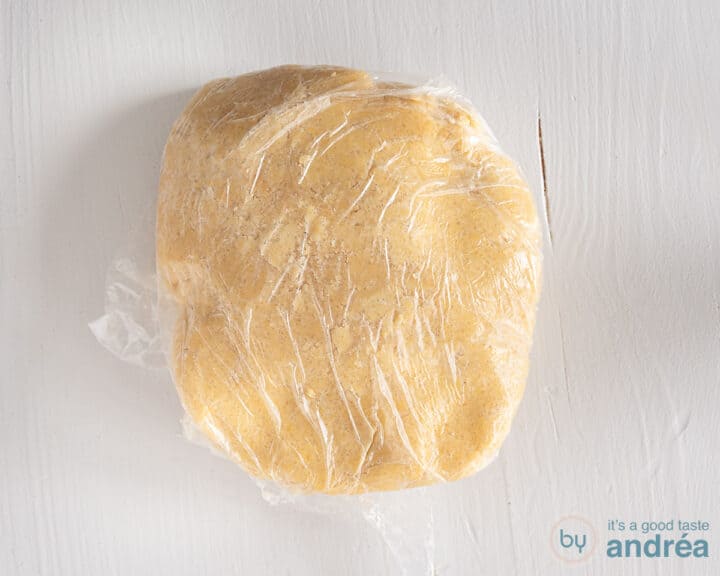 Dough wrapped in plastic foil on a white surface