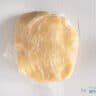 Dough wrapped in plastic foil on a white surface