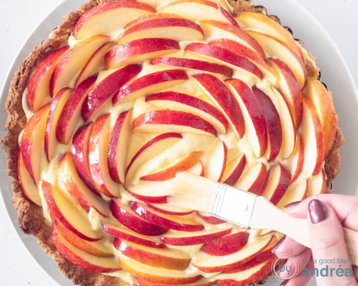 Apricot jam is brushed over the apple slices with a brush.