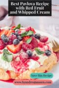 Part of meringue with mixed fruit and whipped cream. A text: besta pavlova recipe with red fruit and whipped cream