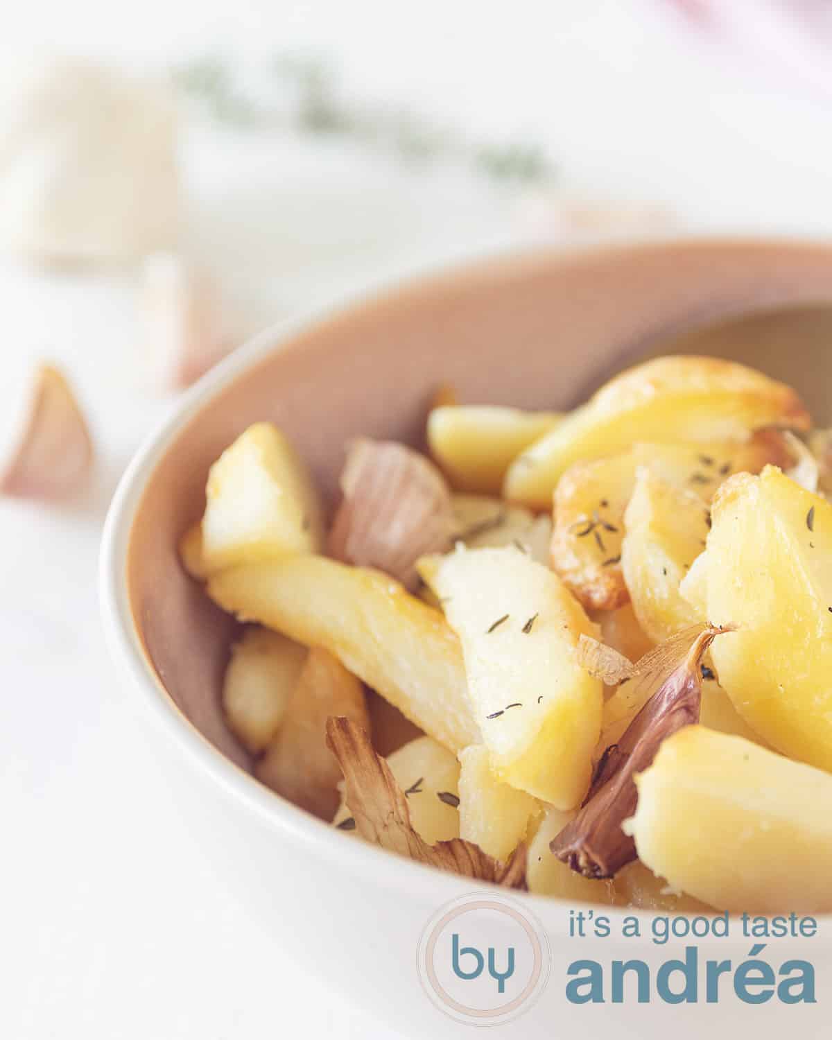 Half a bowl filled with potatoes, baked, garlic and thyme. On a white background