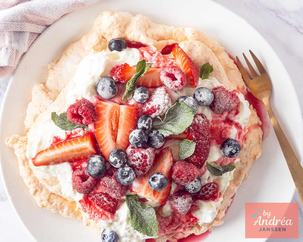 Baked pavlova topped with fruits and whipped cream