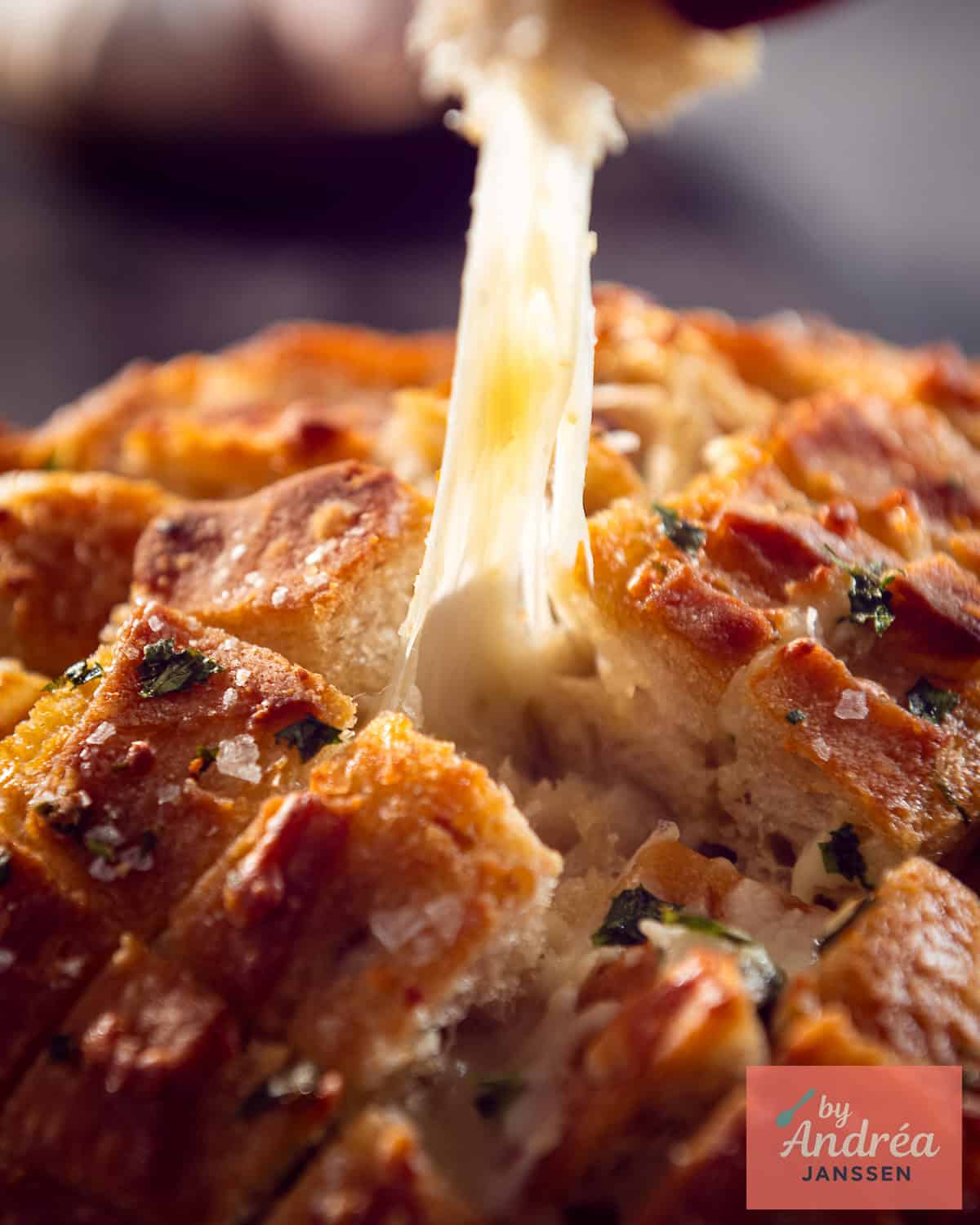 Pulling apart a cheesy garlic bread piece with long mozzarella cheese pulls