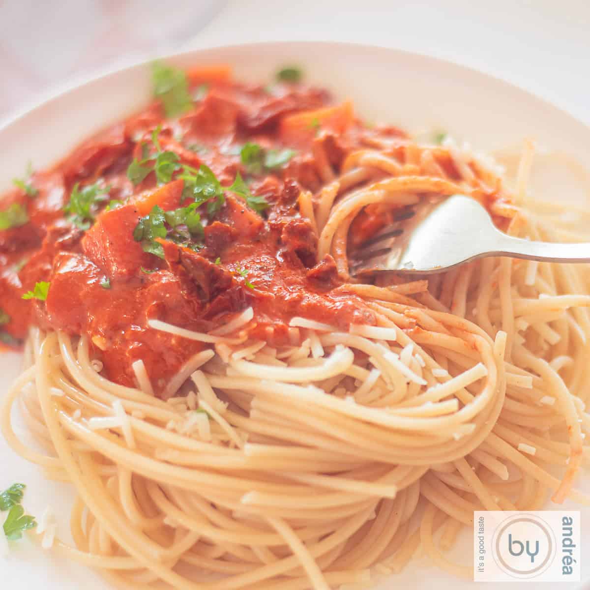 A square photo with a plate of spaghetti with sauce containing mascarpone, ground beef and tomato.
