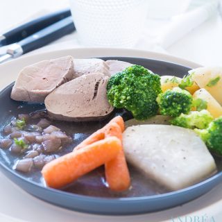 A plate full of vegetables, potatoes and poached pork tenderloin