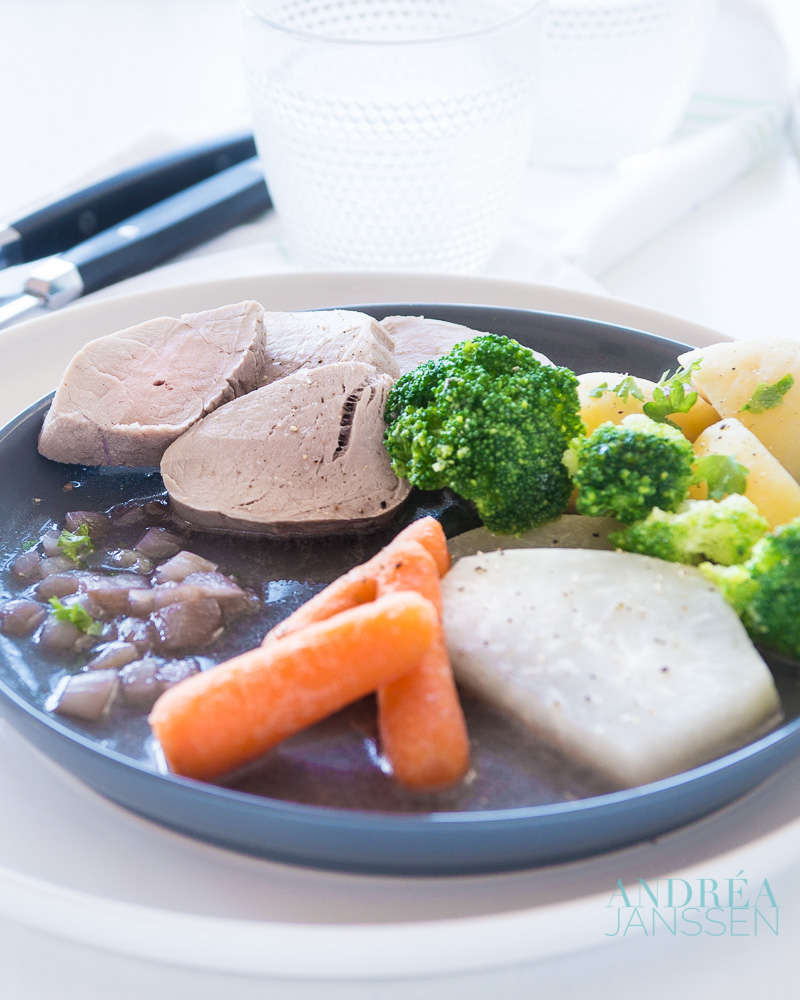 A plate full of vegetables, potatoes and poached pork tenderloin