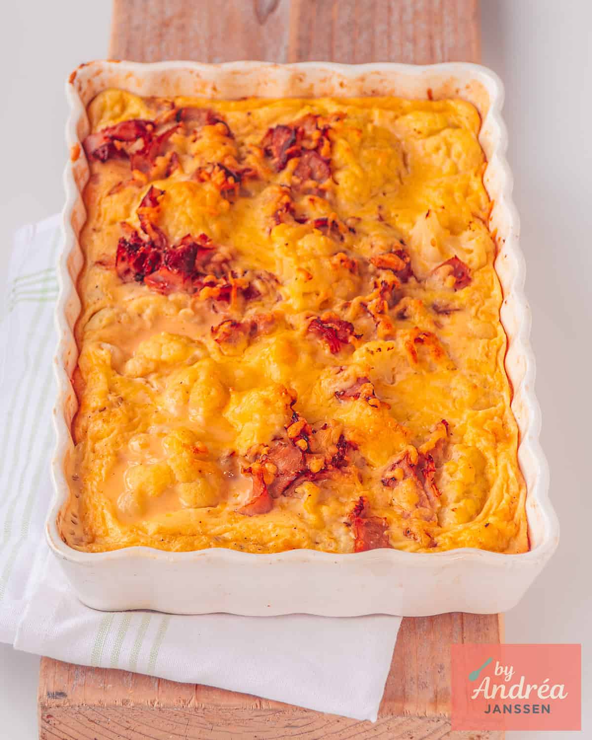 Een ovenschaal met bloemkool, romige saus, spekjes en gegratineerd met kaas.