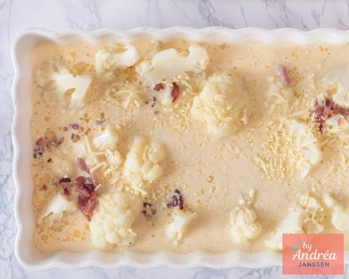 Een ovenschaal met saus, bloemkool en spekjes.