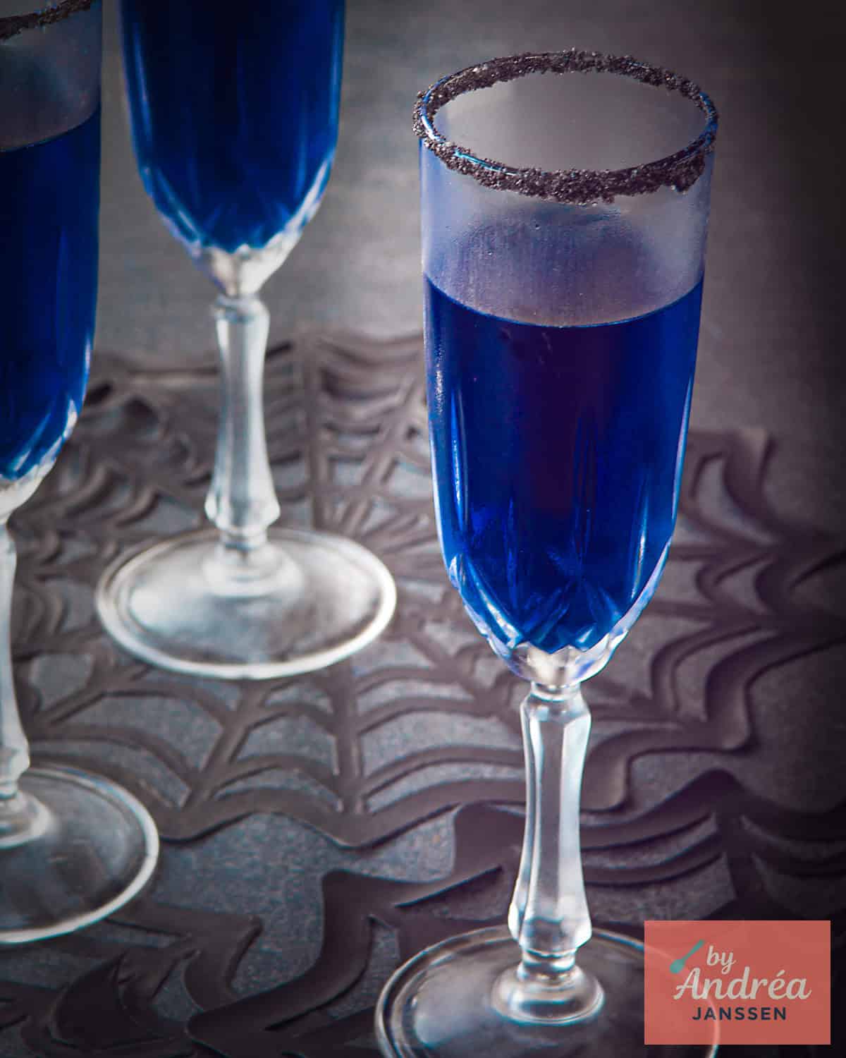 A blue cocktail in a champagne glass.