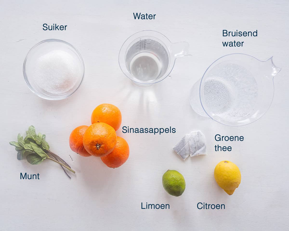 Ingredienten Sinaasappel IJsthee Maken op een witte ondergrond met tekstbeschrijving.