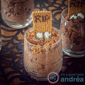 A square photo of a chocolate mousse dessert with a tombstone, RIP and flowers in a dark background