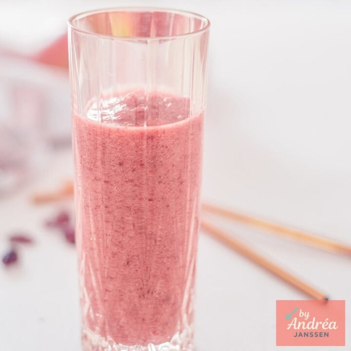 A square photo with a glass of apple cranberry smoothie