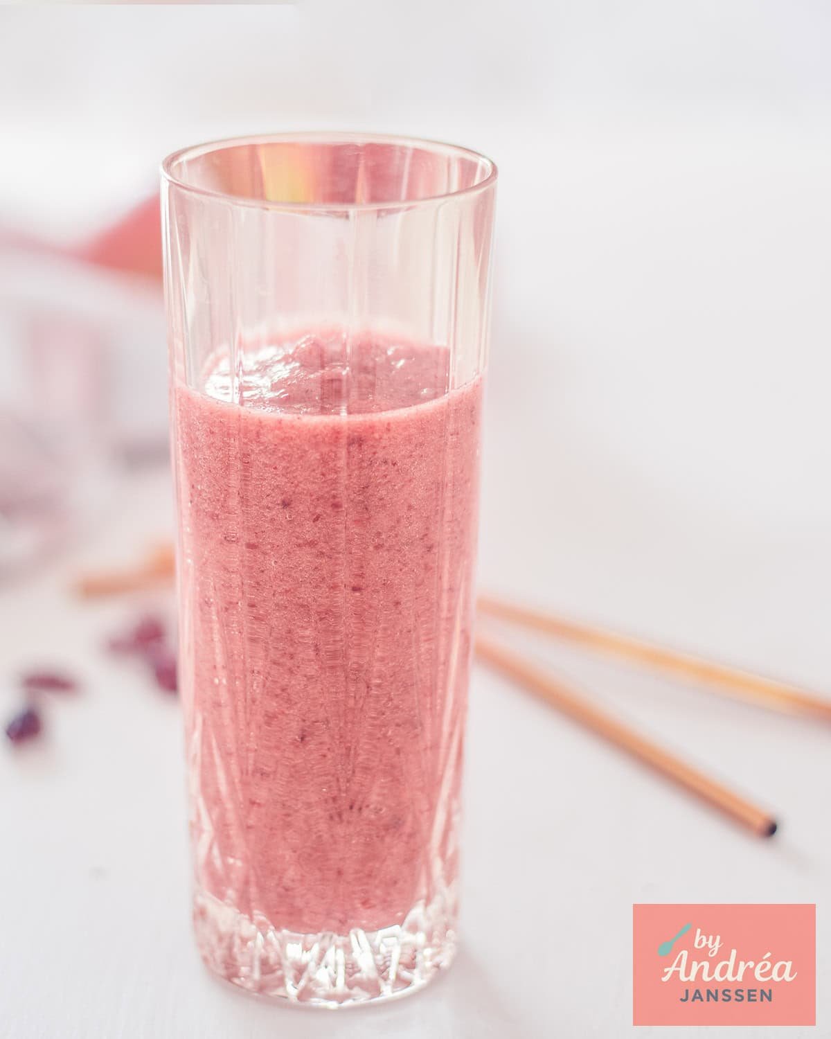 Een foto van een glas roze cranberry appel smoothie