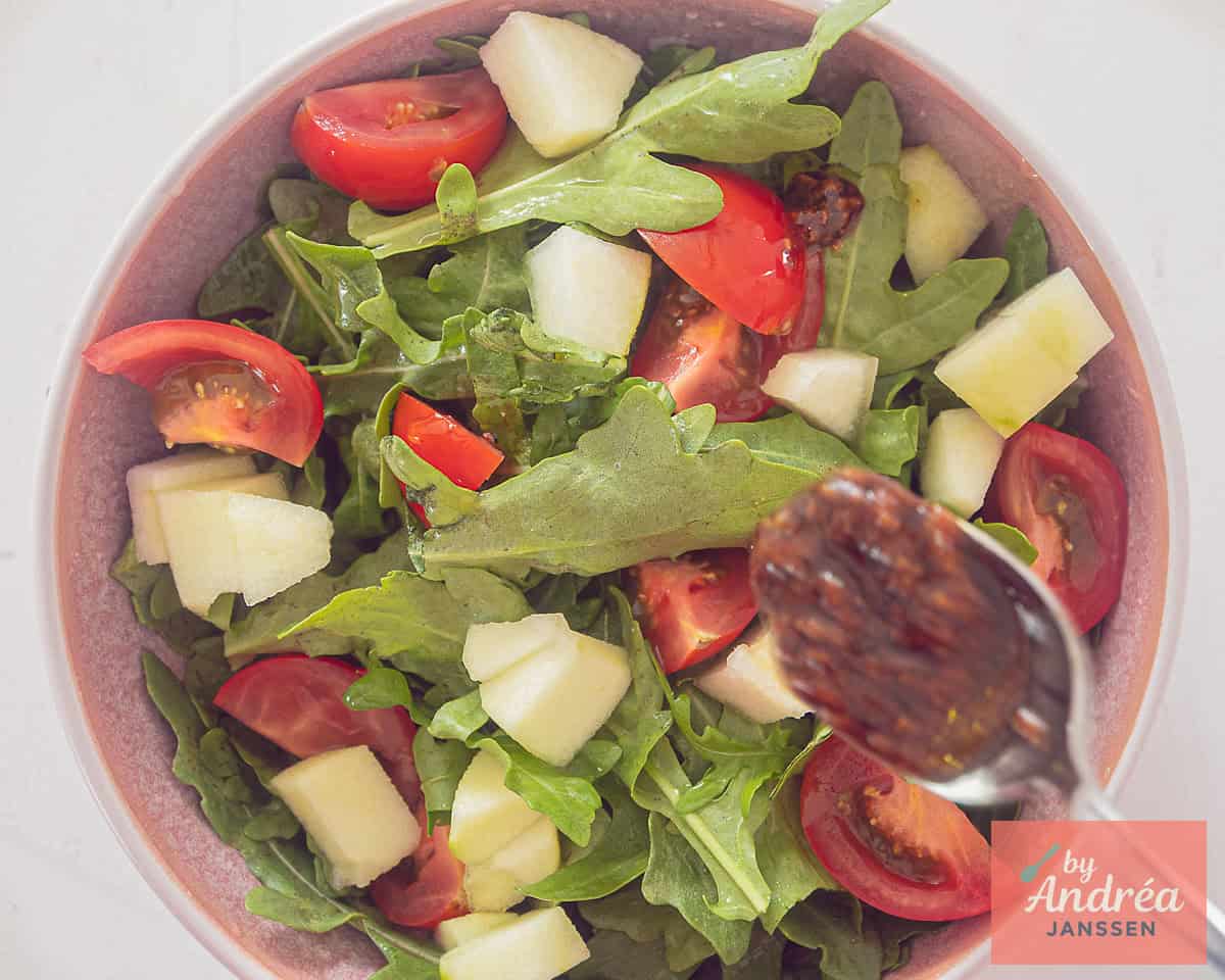The dressing is added to a salad with arugula, pear, apple and tomato