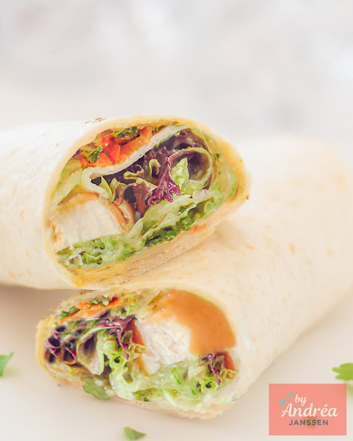 Twee wraps liggend op elkaar, inhoud zichtbaar: salade, wortel en gerookte kip.