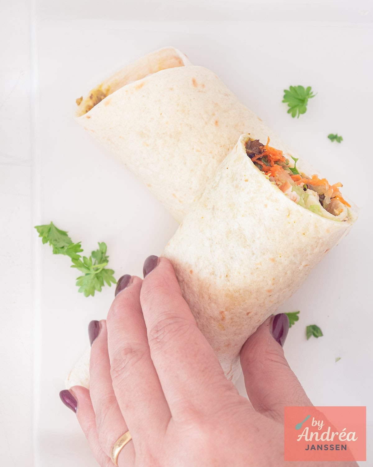 Een foto van bovenaf van twee halve wraps op elkaar. Een hand pakt een wrap vast.
