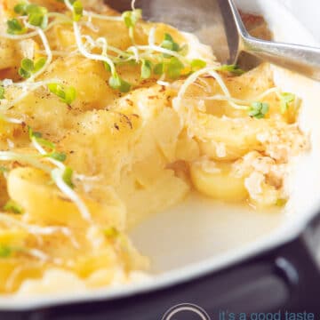 a casserole dish with potato gratin with emmentaler with a spoon taken out of it.