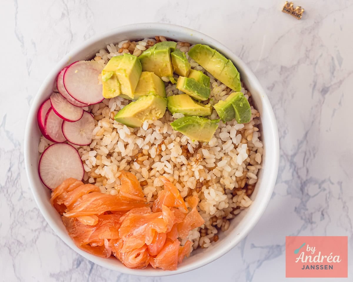 White bowl with sushi rice, smoked salmon, avocado and radish slices