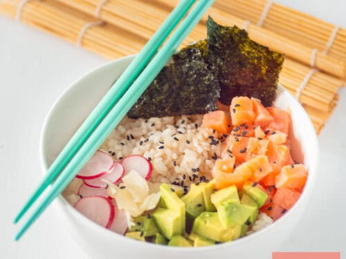 A square picture with a white bowl filled with sushi rice, avocado, radishes, smoked salmon, nori sheet, sushi rice