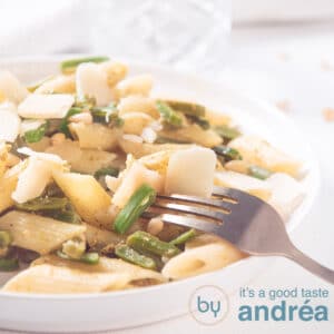 A square photo with pasta pesto and runner beans on a white background