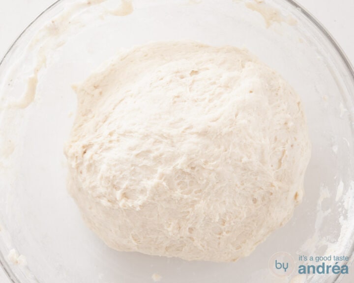 A glass bowl with a ball of dough.
