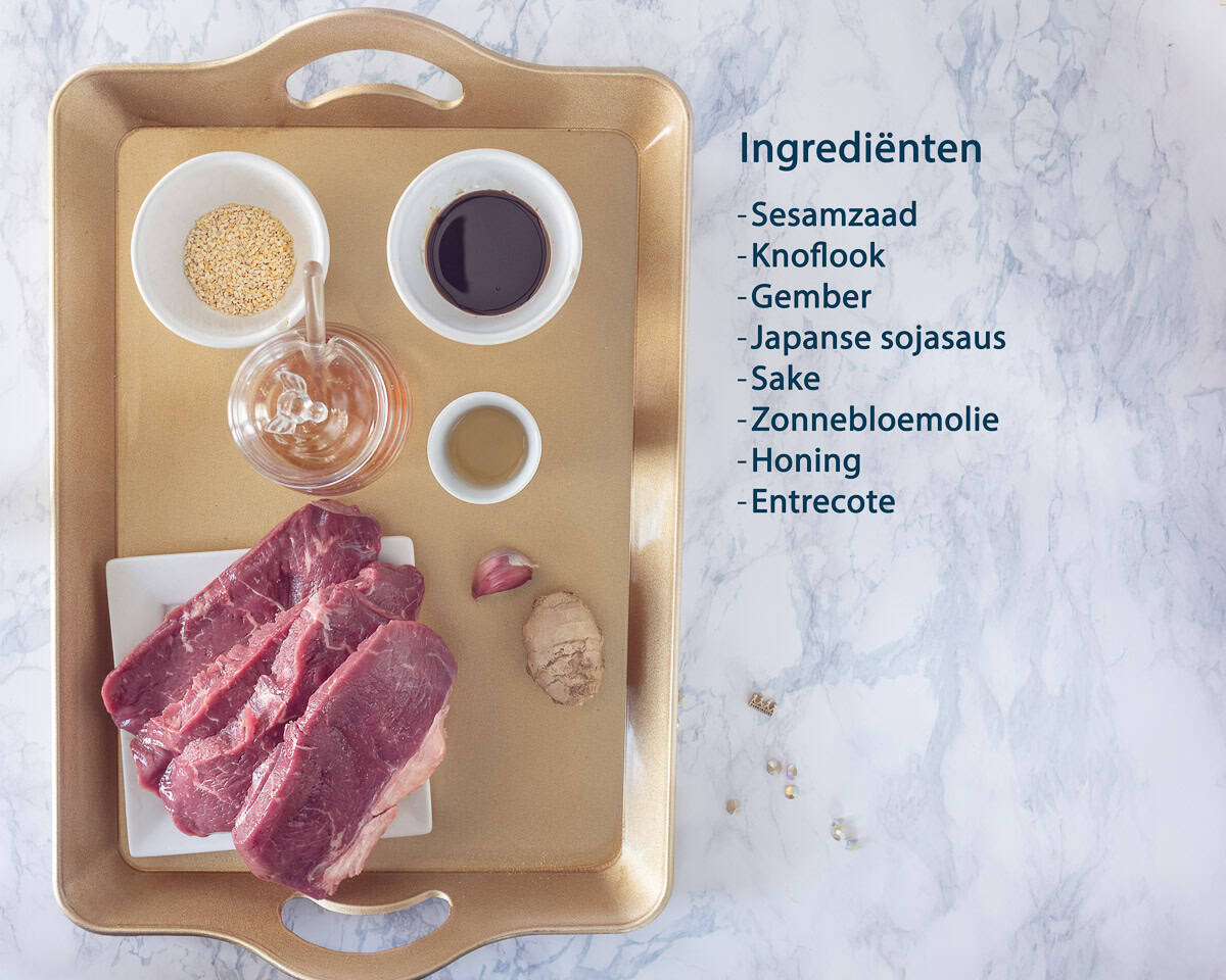 Een gouden dienblad met de ingredienten voor entrecote met sesam sojasaus marinade. Ernaast een tekst beschrijving van de ingredienten.