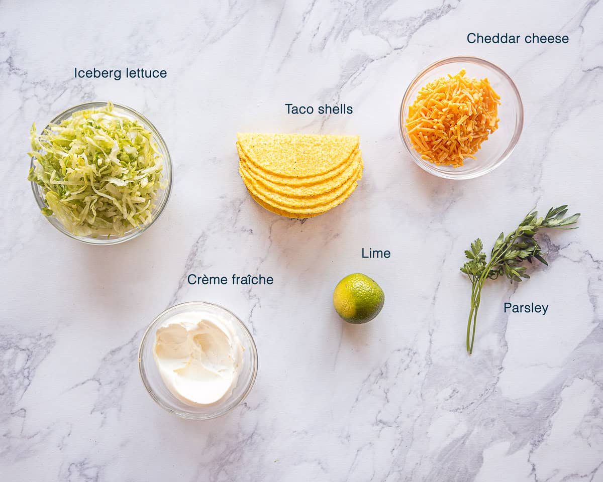 Ingredients at the table vegetarian taco shells on a marble white background with text description