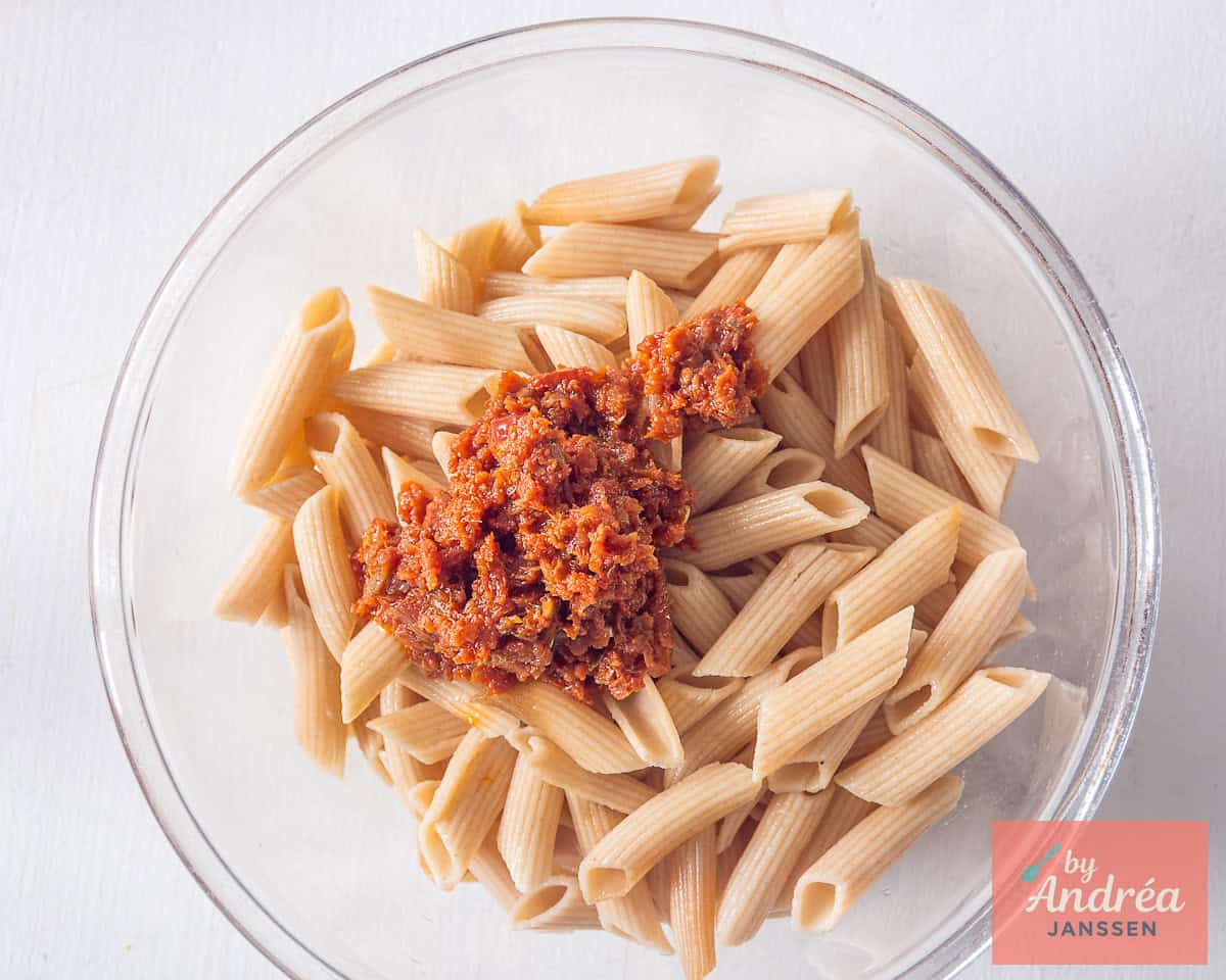 Een glazen schaal met penne en tomatentapenade
