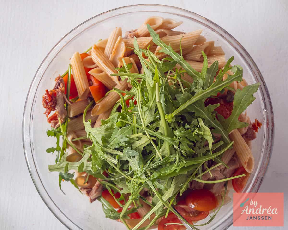 Rucola wordt aan de pasta toegevoegd.