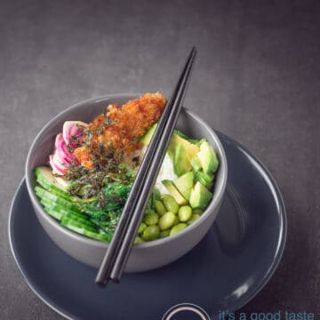 A gray bowl filled with cucumber, sriracha, lima beans, avocado and beets. Topped with seaweed.
