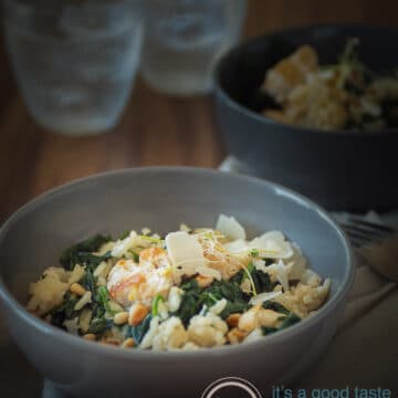 a grey bowl filled with creamy risotto with spinach and chicken. Another bowl in the back as are two glasses
