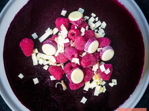 A square picture of a no bake cheesecake with white chocolate and forrest fruits.