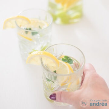 A square photo with two glasses filled with grape and lemon fruit water on a white background.